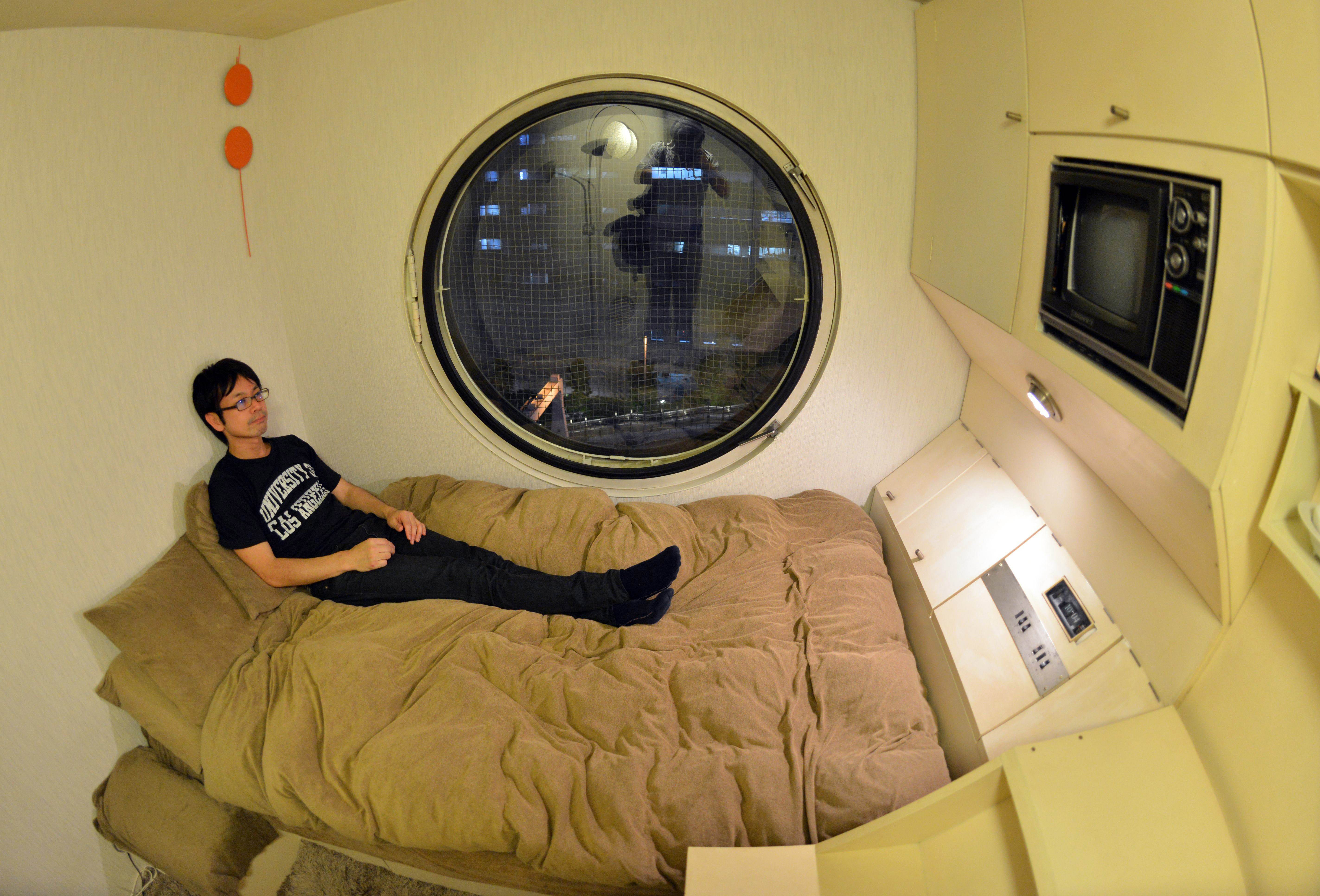 TO GO WITH STORY Japan-architecture-capsule-Nakagin,FEATURE by Katie Forster This picture taken on September 9, 2014 shows a resident of the Nakagin Capsule Tower Masato Abe at his room in Tokyo. The 140 units at Nakagin represent a special part of the history of architecture and one that is worth protecting against plans to tear it down. Around half of the capsules, designed by Japanese architect Kisho Kurokawa in 1972, are currently in use as offices, art studios and second homes, but 20 of the tiny spaces are full-time homes.   AFP PHOTO / Yoshikazu TSUNO